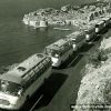 Tourist buses move slowly in a column along  the road above Dubrovnik (1960s)