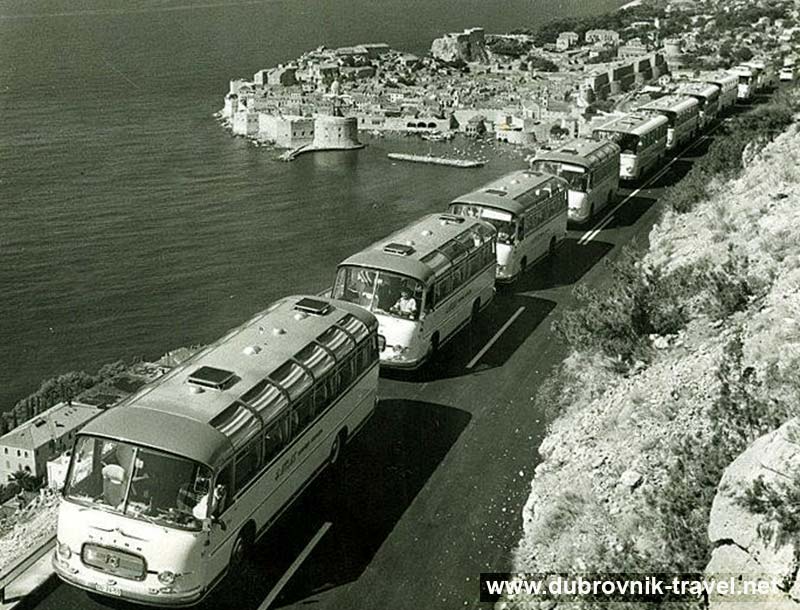 Tourist buses move slowly in a column along the road above Dubrovnik (1960s)